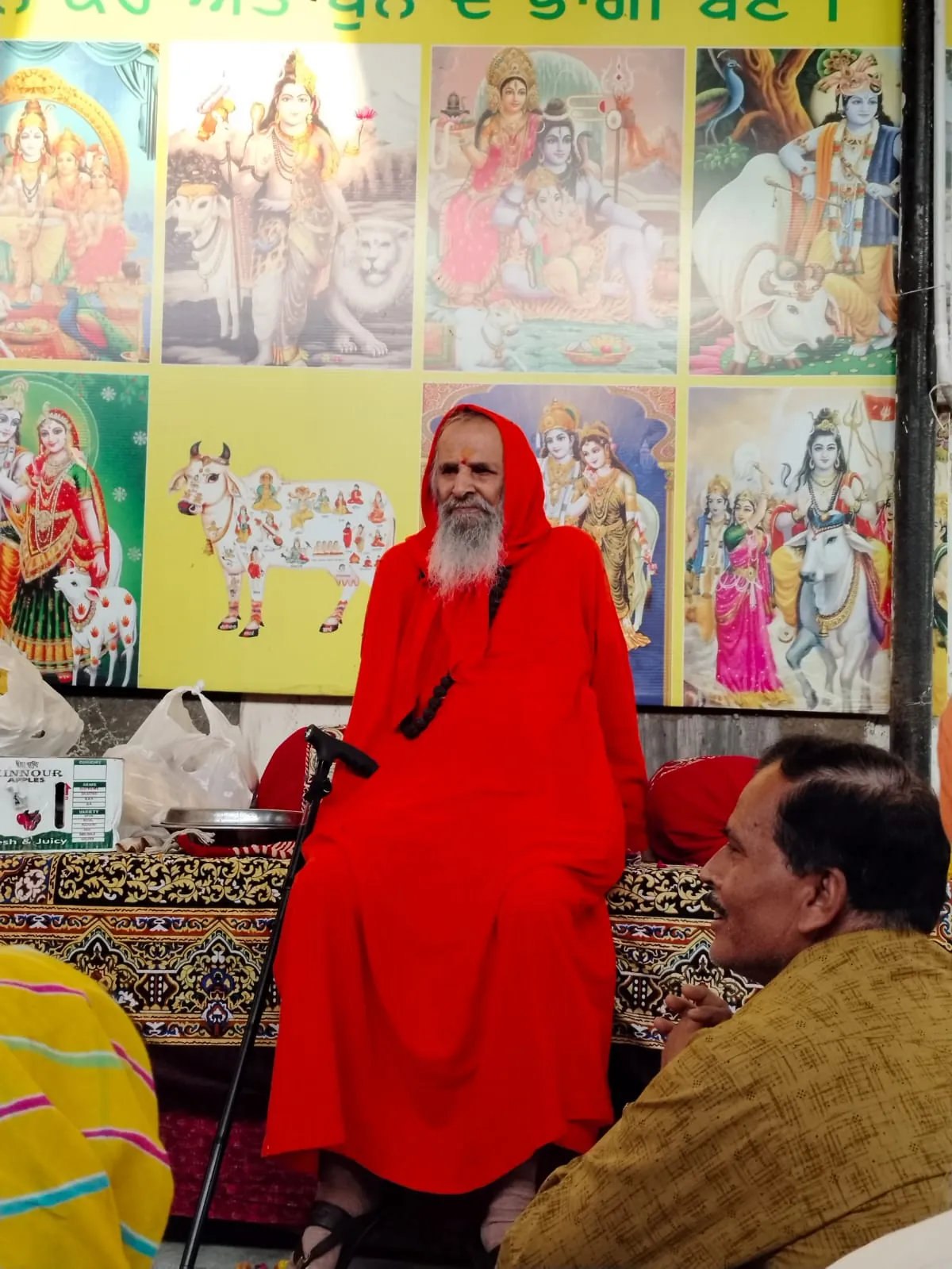 A visiting sant seated before images of the deities during a gathering at the gaushala.